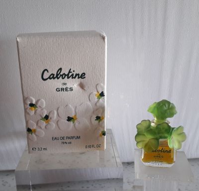 un petit flacon de parfum à côté d'une petite boîte de parfum