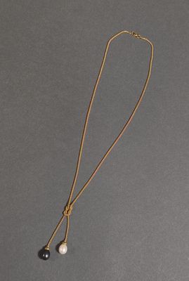 un collier de perles noires et blanches monté sur une chaîne en or