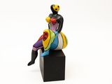 figurine représentant une femme assise sur un bloc noir