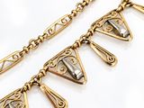 a close up of a gold necklace with a triangle design on it