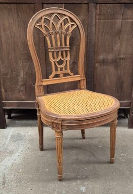 a wooden chair with a wicker seat in front of a wooden fence