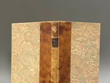 an old book sitting on top of a white table next to a gray wall