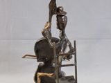 statue of a man sitting on a chair with a bird on his head