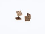 two gold cufflinks with diamonds on them on a white background