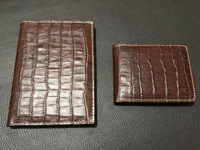 two brown leather wallets sitting on top of a black table