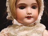 a close up of a doll wearing a white dress and bonnet