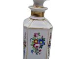 a small white bottle with flowers on it on a white surface