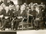 a lot of men sitting on chairs in front of a crowd