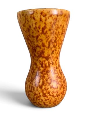 un petit vase posé sur une surface blanche