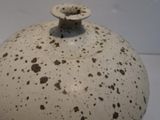 a white vase with brown spots on it on a white surface