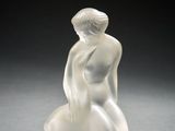une image représentant une sculpture en verre représentant une femme assise sur un rocher