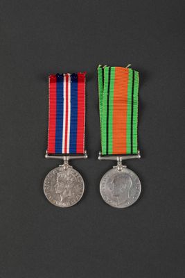 two medals with ribbons and a coin on a black background