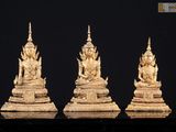 trois statues en or représentant des bouddhas assis sur un socle noir