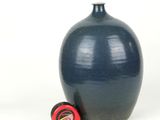 a blue vase with a tape on the side and a measuring tape in front of it