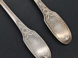 two silver spoons sitting on top of a table next to each other