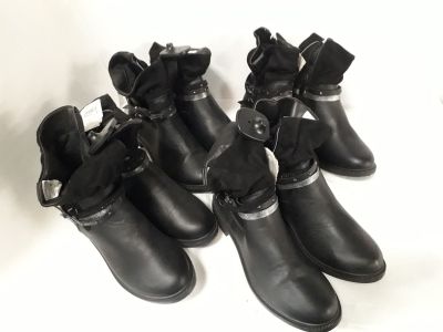 five pairs of black boots with bows on them on a white surface