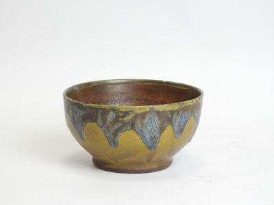 a brown and blue bowl sitting on a white surface