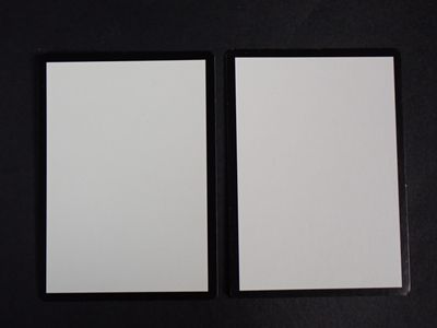 two pieces of white paper sitting next to each other on a black surface