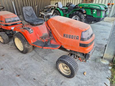 une tondeuse à gazon orange garée à côté d'autres tondeuses à gazon dans un garage