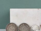 Trois pièces de monnaie sont posées sur une dalle de marbre, près d'un mur vert.