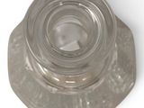 a clear glass bottle with a metal lid on a white surface