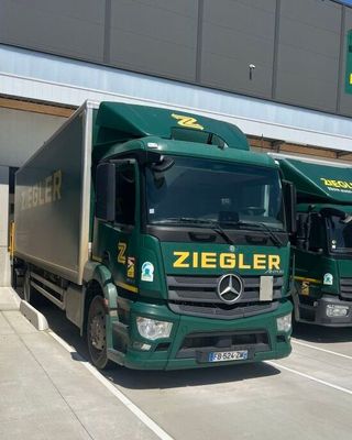 two green trucks parked in a parking lot next to each other