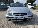 a silver car that is parked in a gravel lot