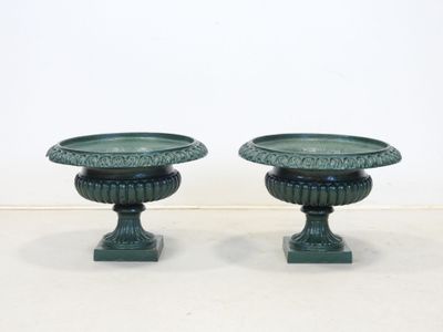 une paire d'urnes vertes posées sur des socles, sur une surface blanche