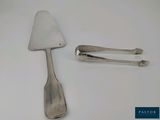 une cuillère en argent et une spatule posées sur une table blanche