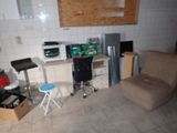 a room with a chair, a table, a microwave, a refrigerator, and a chair in it