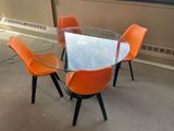une table en verre entourée de quatre chaises orange