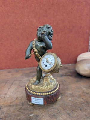une petite statue représentant un garçon avec une horloge posée sur une table