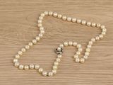 a close up of a white pearl necklace on a wooden table