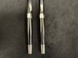 two fountain pens sitting on top of a black surface