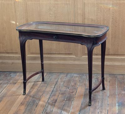 une petite table avec un plateau en verre posée sur un parquet