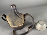 a metal kettle with a chain around it and a cup next to it