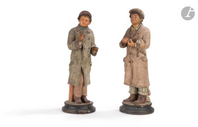two figurines of two people standing next to each other on a white surface