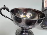 a silver cup sitting on top of a table next to a picture frame