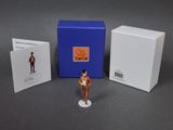 une figurine représentant un homme en costume-cravate à côté d'une boîte