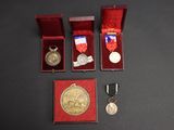 trois médailles et une médaille dans une boîte rouge sur une surface noire