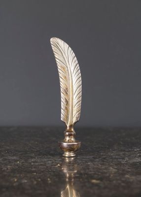 un objet en forme de plume dorée posé sur une table