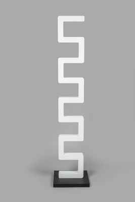 a tall white sculpture with a black base on a gray surface