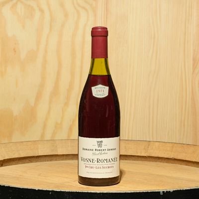 a bottle of wine sitting on top of a barrel