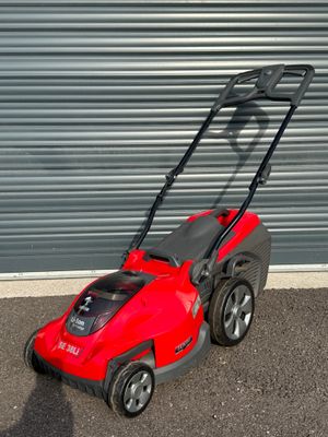 une tondeuse à gazon rouge garée devant la porte d'un garage