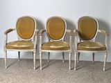 three chairs with yellow upholstered cushions are sitting against a wall