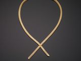 a gold necklace with a cross on a black background