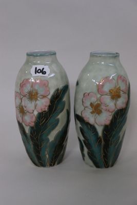 two vases with flowers painted on them sitting on a table