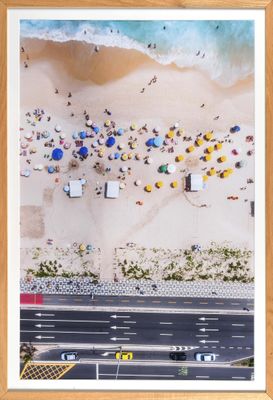 une vue aérienne montrant des personnes sur la plage avec des parasols et des voitures