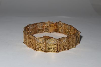 bracelet doré orné d'un motif en filigrane sur un fond blanc