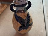 un vase avec un oiseau posé sur une table